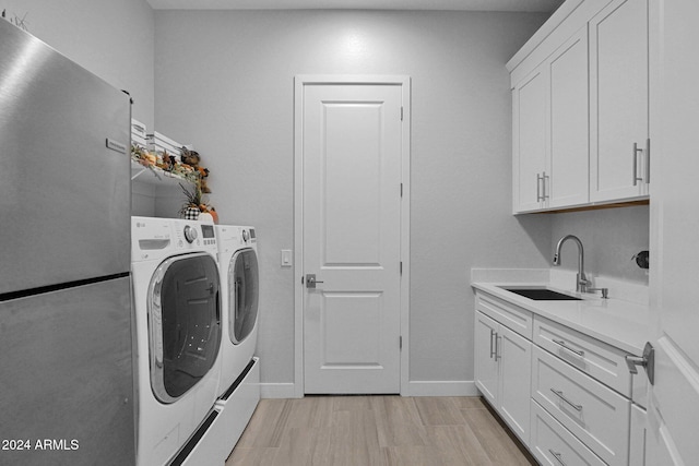 laundry room with cabinets, sink, independent washer and dryer, and light hardwood / wood-style floors