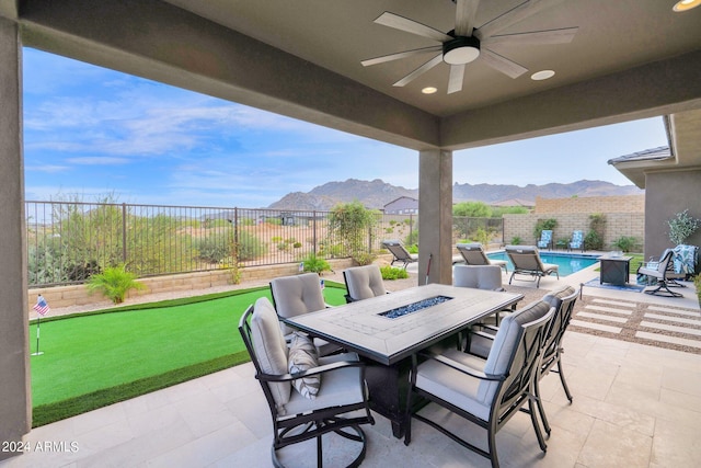 view of patio / terrace featuring ceiling fan, a fenced in pool, a mountain view, and an outdoor fire pit