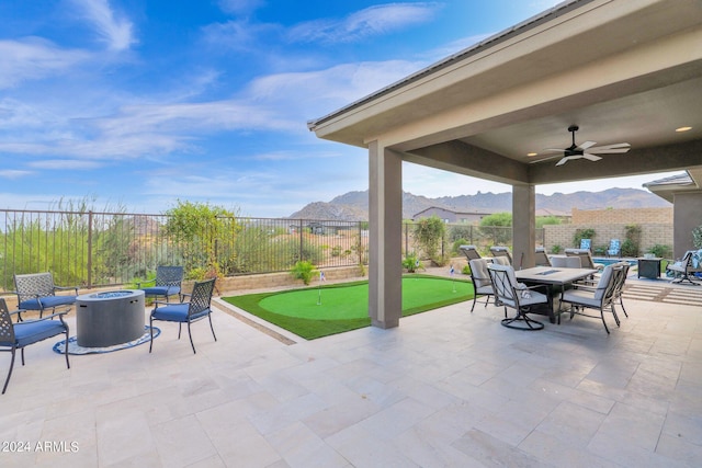 view of patio featuring ceiling fan, a mountain view, and a fire pit