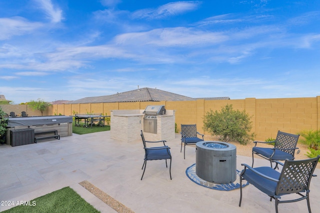 view of patio featuring a hot tub, a fire pit, an outdoor kitchen, and grilling area