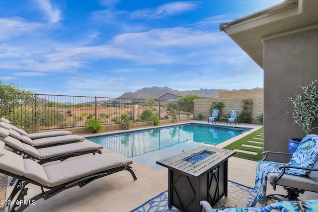 view of swimming pool with a patio, a mountain view, and a fire pit