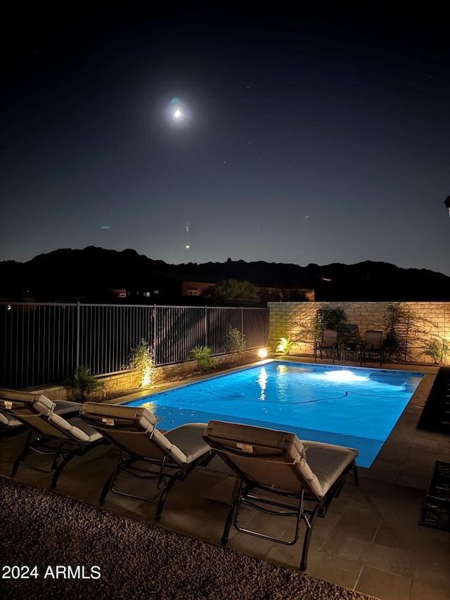 pool at twilight with a patio area and a mountain view