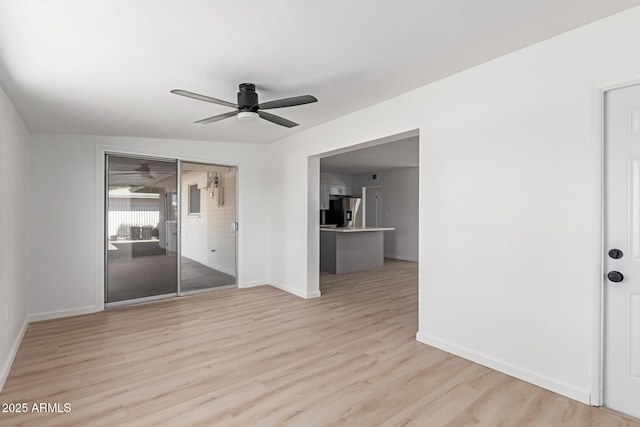 empty room with a ceiling fan, light wood-type flooring, and baseboards