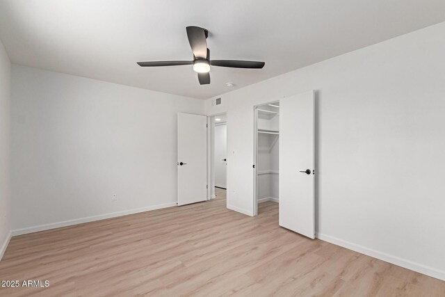 unfurnished bedroom with a closet, light wood-type flooring, a ceiling fan, and baseboards