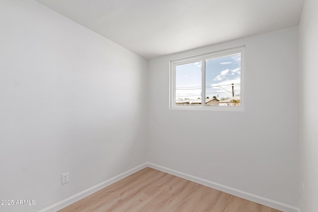 spare room featuring light wood-style floors and baseboards
