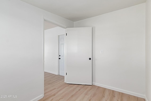 empty room featuring light wood-type flooring and baseboards