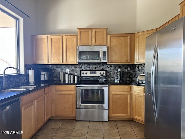 kitchen featuring light tile patterned flooring, appliances with stainless steel finishes, sink, and backsplash