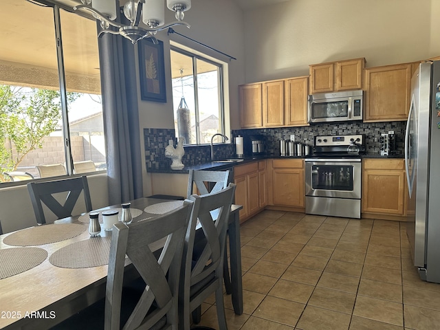 kitchen featuring sink, backsplash, a chandelier, dark tile patterned floors, and stainless steel appliances