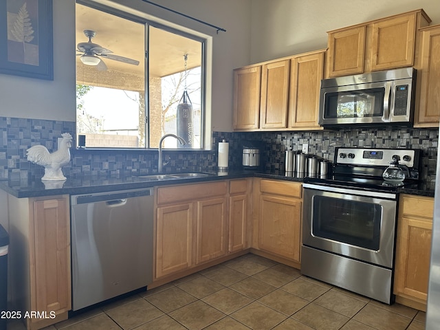 kitchen featuring appliances with stainless steel finishes, sink, decorative backsplash, light tile patterned floors, and ceiling fan