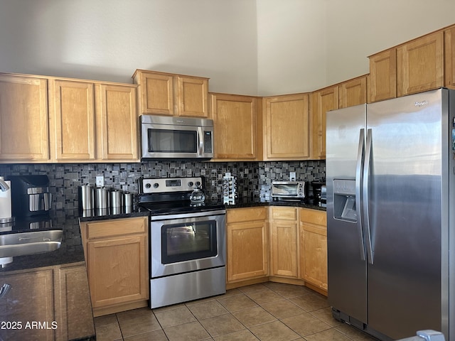 kitchen featuring sink, light tile patterned floors, appliances with stainless steel finishes, a towering ceiling, and decorative backsplash