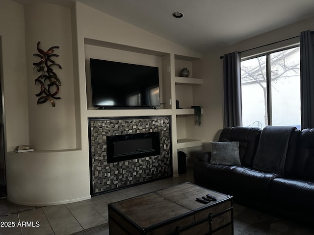 living room featuring tile patterned flooring, built in shelves, vaulted ceiling, and a tile fireplace