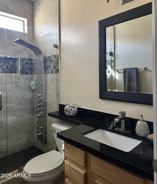 bathroom featuring vanity, a shower with shower door, and toilet