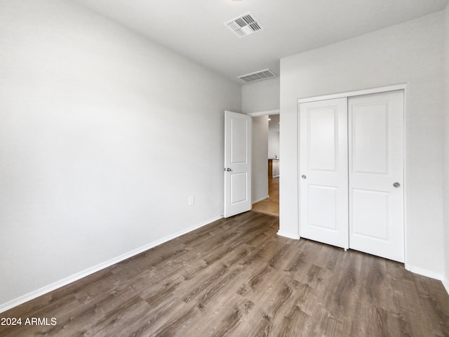 unfurnished bedroom featuring dark hardwood / wood-style flooring and a closet