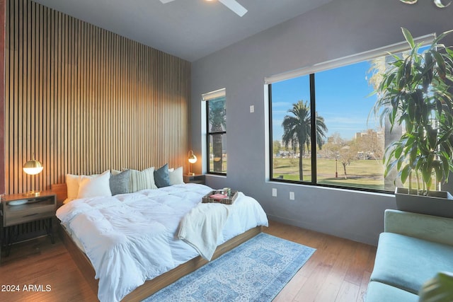 bedroom featuring hardwood / wood-style floors, ceiling fan, and multiple windows