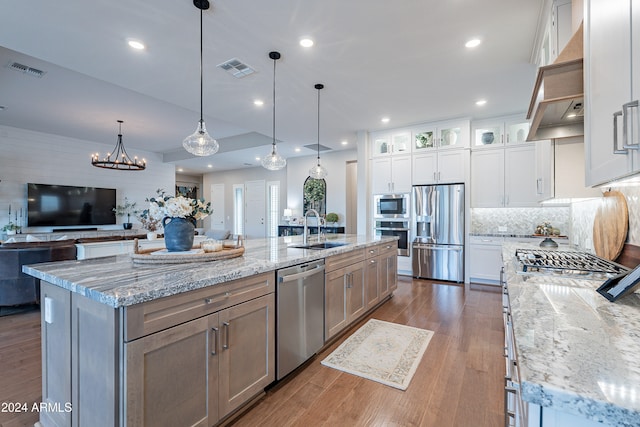 kitchen featuring stainless steel appliances, light stone countertops, a large island, and white cabinets