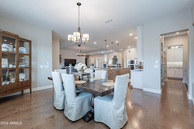 dining area featuring sink, a chandelier, and wood-type flooring