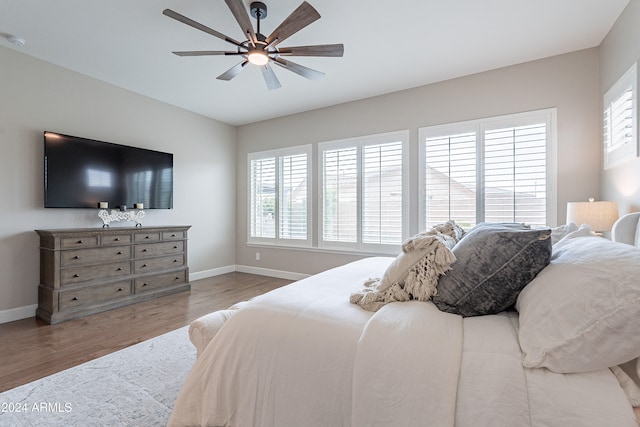 bedroom featuring ceiling fan, multiple windows, and hardwood / wood-style flooring