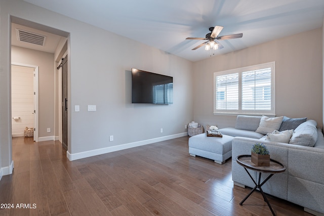 living room with ceiling fan, hardwood / wood-style flooring, and a barn door