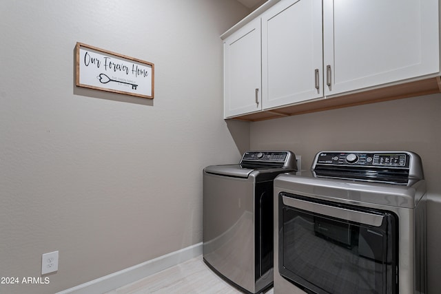 washroom with light hardwood / wood-style floors, washing machine and dryer, and cabinets