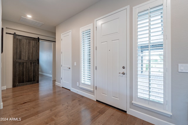 entryway with a wealth of natural light, a barn door, and wood-type flooring