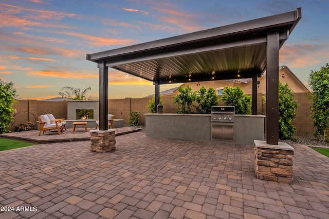 patio terrace at dusk with area for grilling and a fire pit