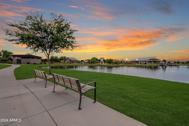 view of home's community with a patio, a lawn, and a water view