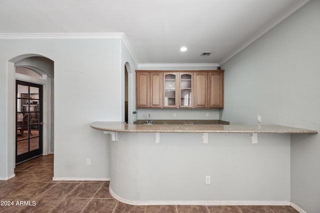 kitchen with a breakfast bar area, arched walkways, and glass insert cabinets