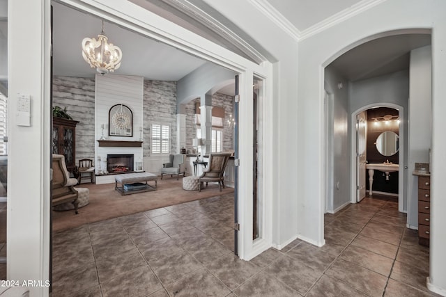 interior space with crown molding, arched walkways, tile patterned flooring, baseboards, and a chandelier