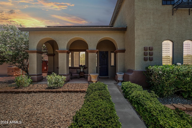 doorway to property featuring a porch and stucco siding