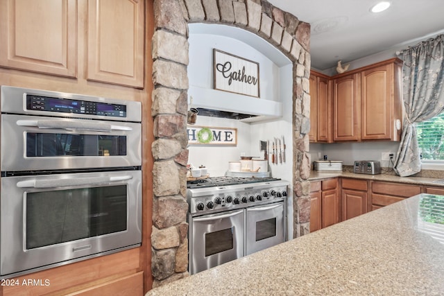 kitchen featuring stainless steel appliances, light stone counters, and recessed lighting