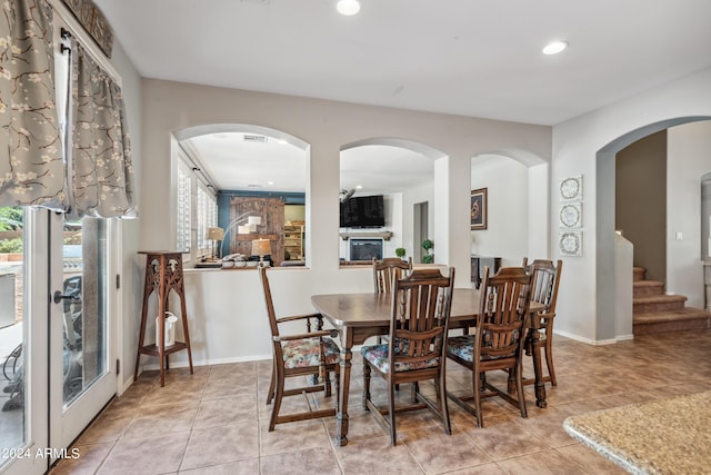 dining room with recessed lighting, light tile patterned floors, a healthy amount of sunlight, and a fireplace