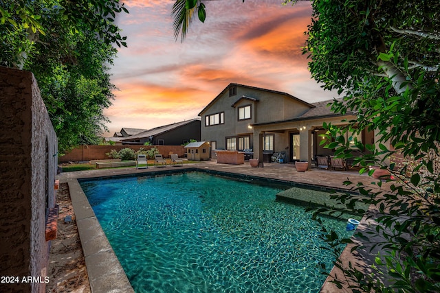 pool at dusk featuring a fenced backyard, a fenced in pool, and a patio area