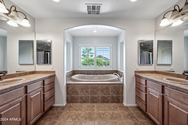 full bathroom featuring visible vents, two vanities, a sink, and a garden tub