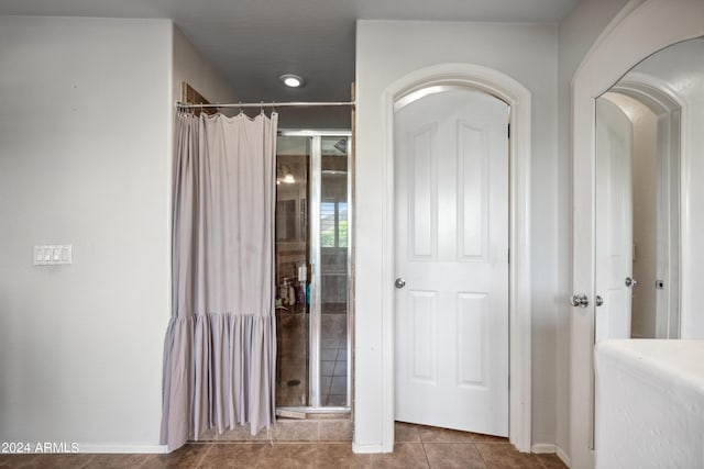bathroom featuring baseboards, tile patterned floors, and a shower stall