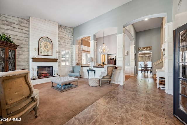 carpeted living room with arched walkways, tile patterned floors, a glass covered fireplace, a chandelier, and a towering ceiling