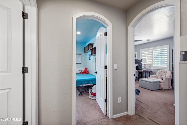 corridor featuring arched walkways, baseboards, and carpet