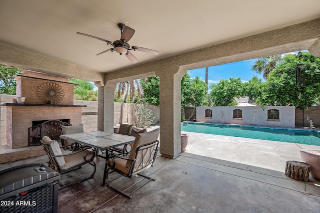 view of patio with a fenced in pool, a fenced backyard, ceiling fan, and exterior fireplace