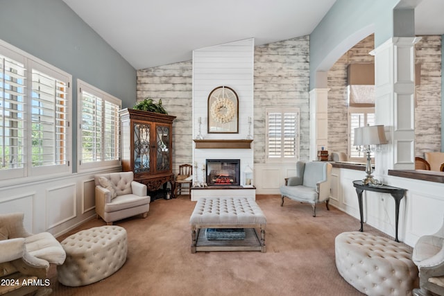 sitting room with light colored carpet, arched walkways, a large fireplace, lofted ceiling, and ornate columns