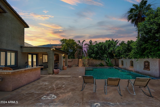 pool at dusk with a fenced in pool, a fenced backyard, and a patio area