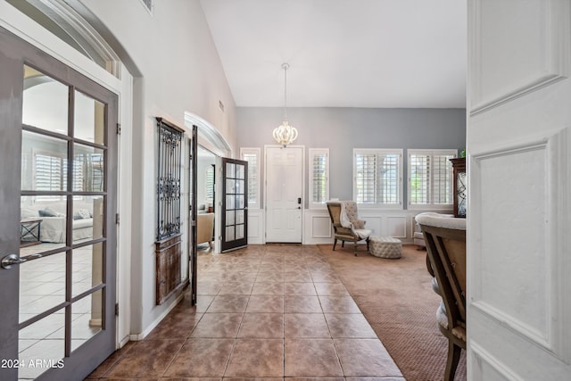 carpeted entrance foyer with an inviting chandelier, lofted ceiling, a decorative wall, and a wealth of natural light