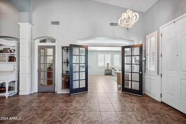 entrance foyer featuring high vaulted ceiling, a notable chandelier, french doors, and visible vents
