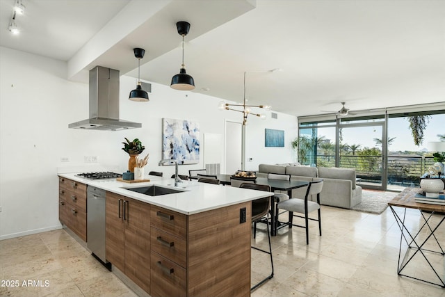 kitchen featuring island range hood, dishwasher, ceiling fan with notable chandelier, expansive windows, and sink