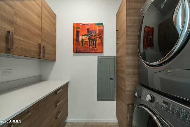 laundry room with cabinets, electric panel, and stacked washer and clothes dryer