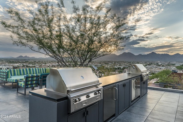 view of patio / terrace with area for grilling, a mountain view, and exterior kitchen