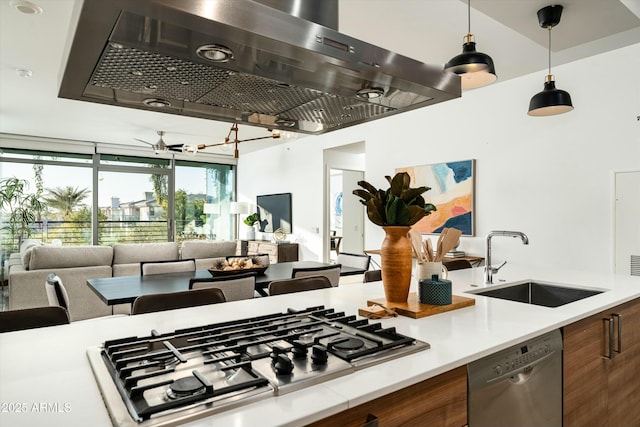 kitchen featuring wall chimney exhaust hood, decorative light fixtures, stainless steel appliances, sink, and ceiling fan