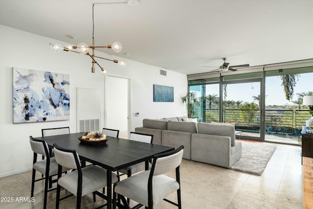 dining area featuring ceiling fan with notable chandelier and a wall of windows