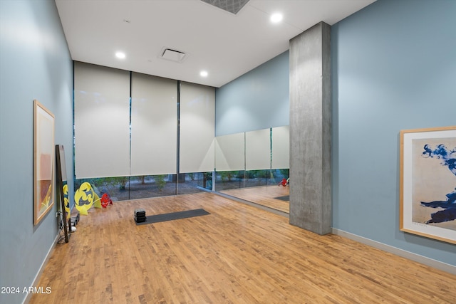 workout room with a towering ceiling and light wood-type flooring