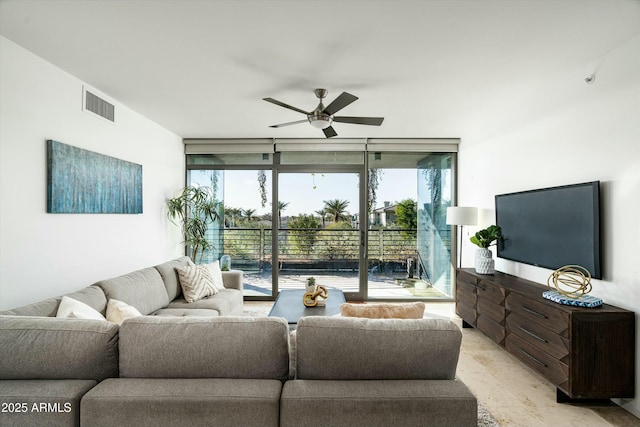 living room featuring ceiling fan and a wall of windows