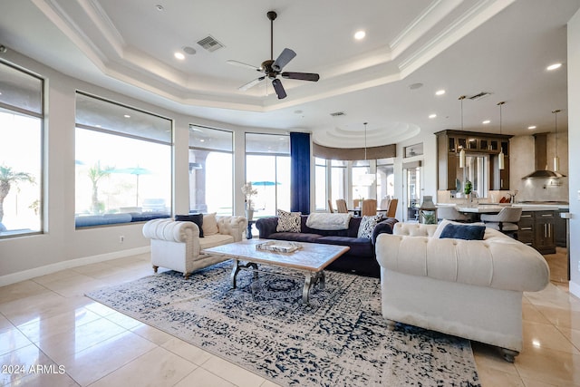 living room with ornamental molding, a tray ceiling, ceiling fan, and light tile patterned floors