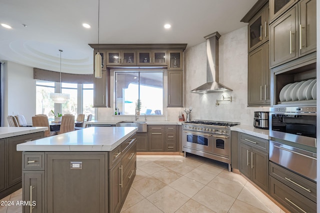 kitchen featuring pendant lighting, sink, a kitchen island, wall chimney exhaust hood, and stainless steel appliances